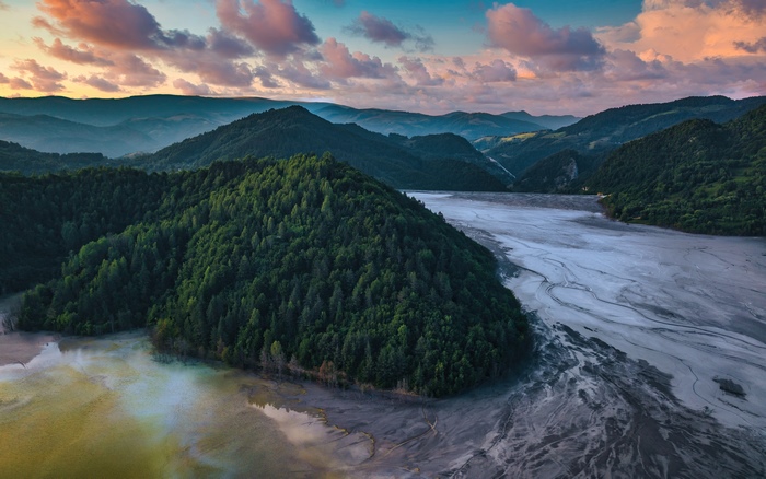 Polluted lake and forested mountains at sunset
