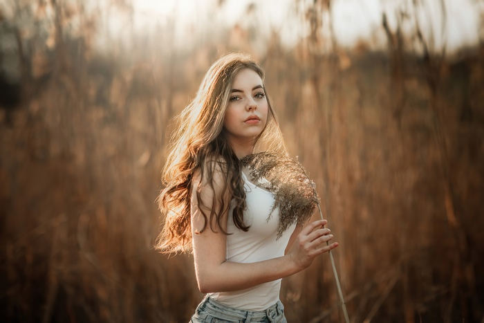 Young woman holding a dried plant in a field