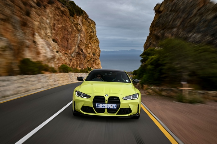 Yellow BMW M4 driving on a coastal road