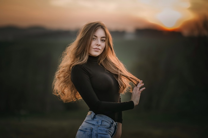 Girl in black turtleneck and jeans at sunset