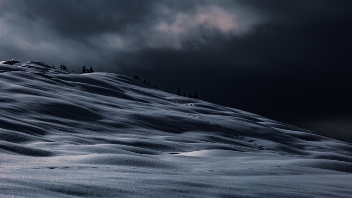 Snowy mountain slope under dark clouds