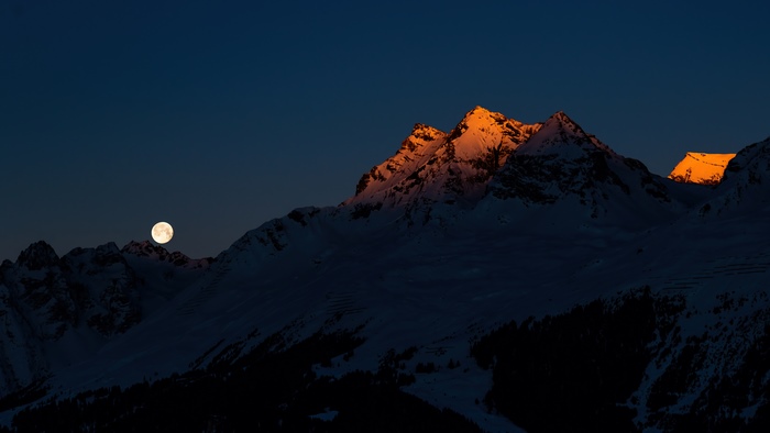 Moon over snow-capped mountains at sunset 4K