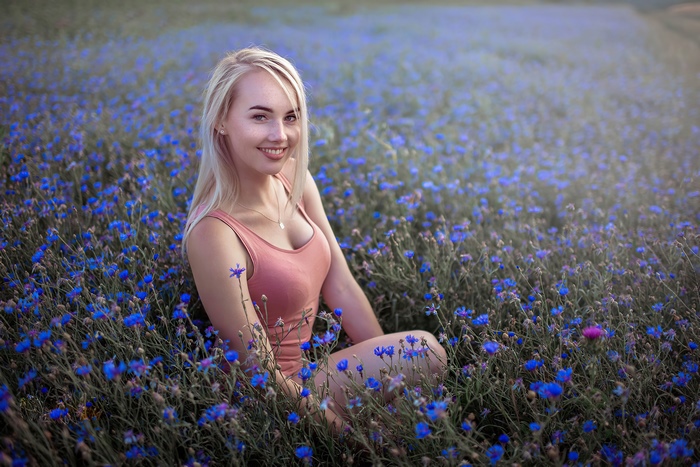 Blonde girl smiling in a field of blue flowers