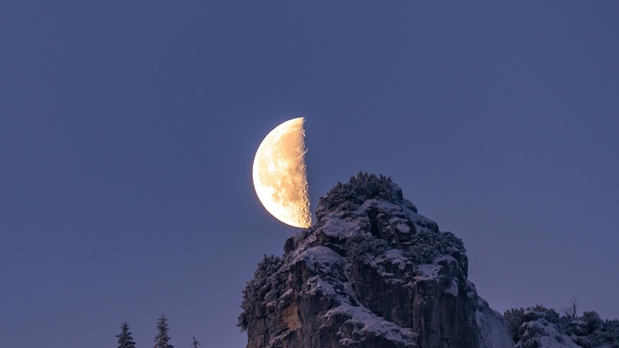 Half moon over snow-covered mountains