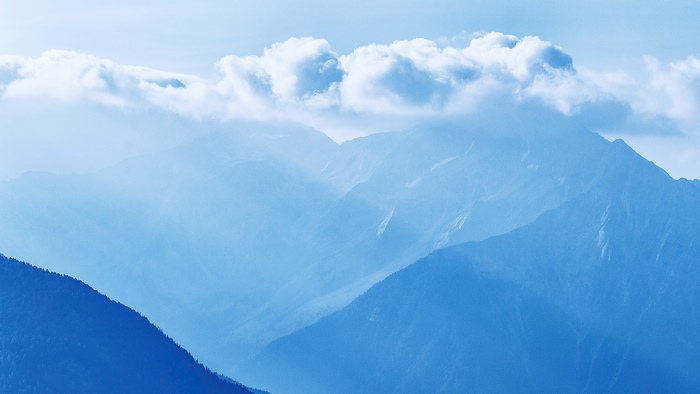 Misty mountains with clouds in blue sky