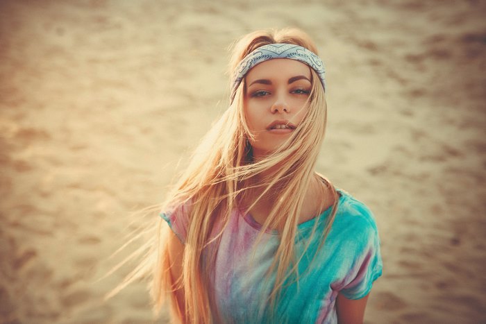 Woman with blonde hair wearing a bandana and tie-dye shirt