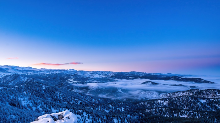 Snowy mountains with fog at sunrise