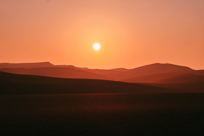 Desert dunes at sunset with sun