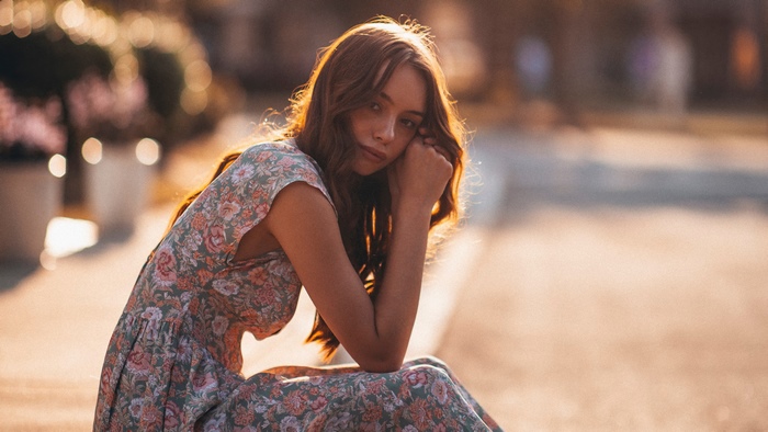Girl in floral dress sitting outdoors