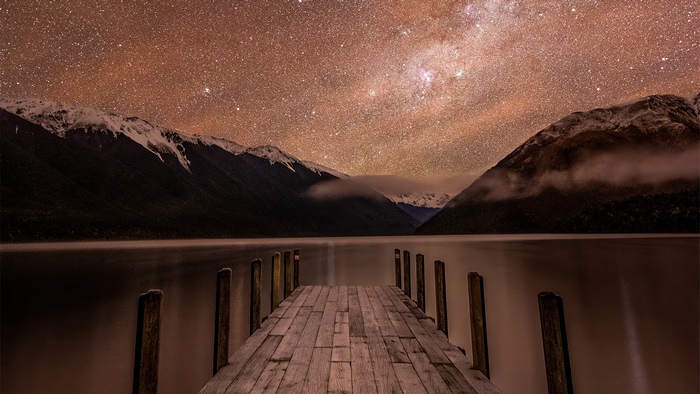 Wooden dock under starry sky and mountains 4K