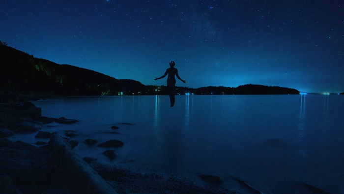 Silhouette of a person in the water under the stars