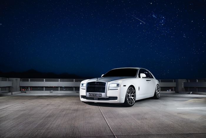 White Rolls-Royce Ghost parked under a starry night sky