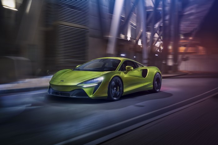 Green McLaren Artura driving through a city at night