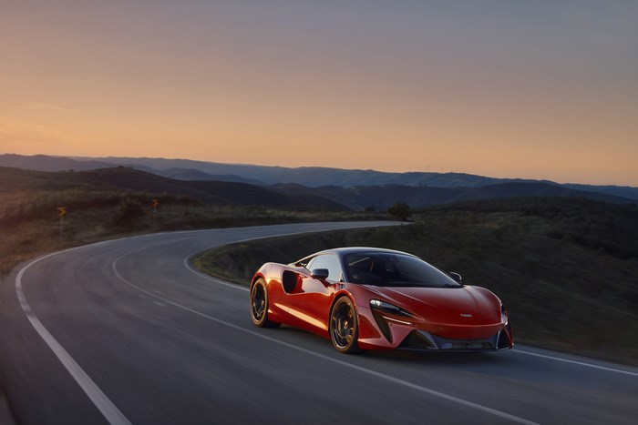 McLaren Artura driving on a winding road at sunset