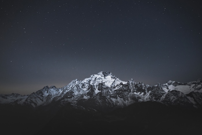 Snow-capped mountains under a starry night sky