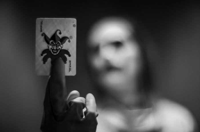 Joker card held by a finger, blurred person in background