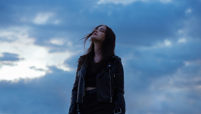 Girl in leather jacket against cloudy sky