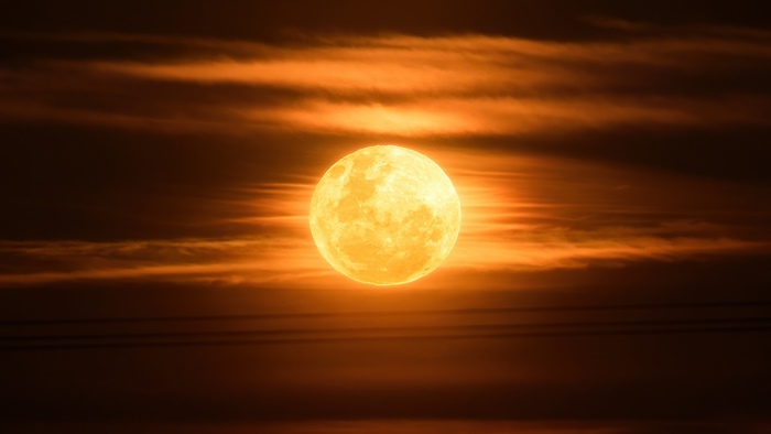 Full moon behind orange clouds 4K