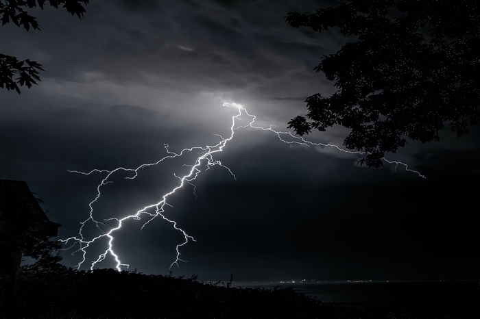 Lightning strikes across a dark night sky over water