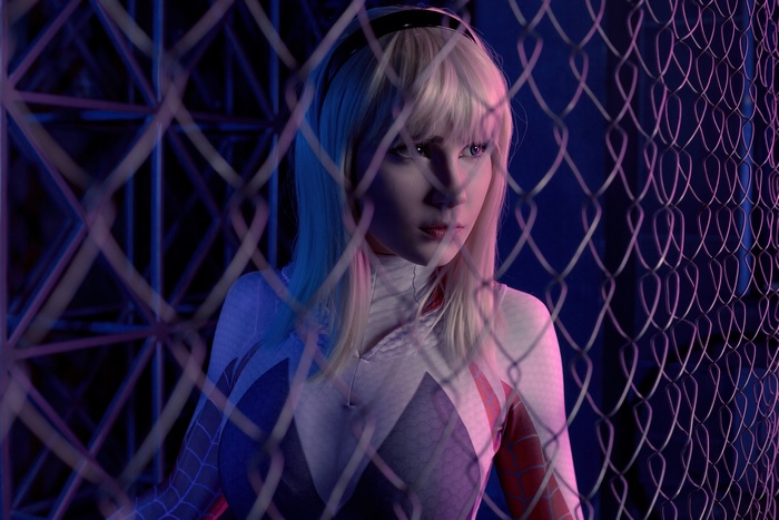 Gwen Stacy cosplay behind a chain-link fence