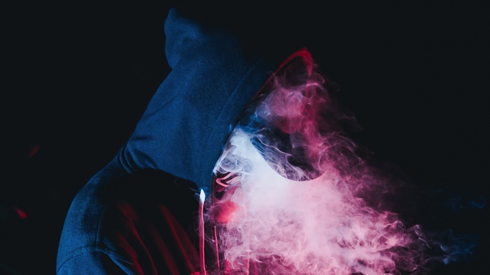 Person in a hoodie with colorful smoke