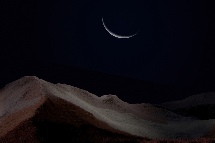 Crescent moon over desert landscape
