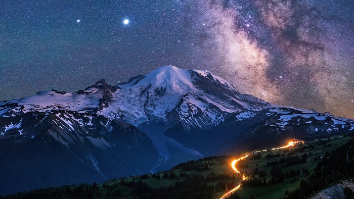 Milky Way over snow-capped mountains and a winding road