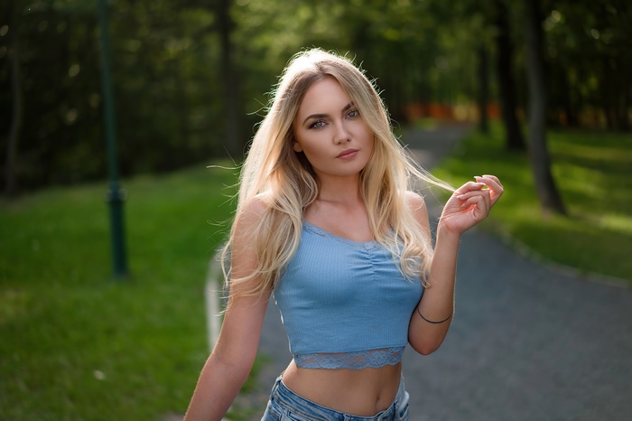 Blonde model in blue top and jeans in park