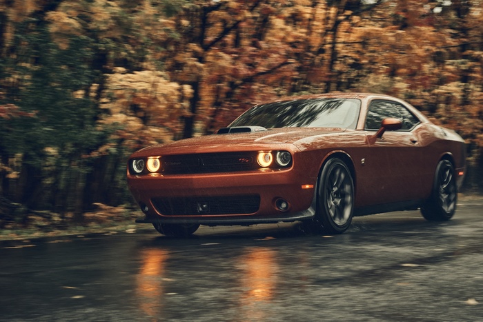 Orange Dodge Challenger driving on a wet road