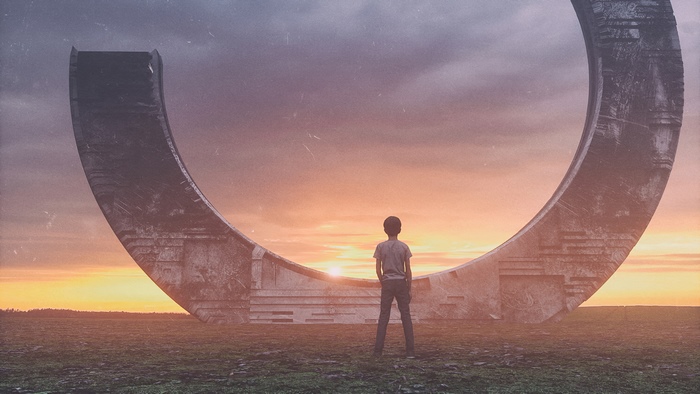 Boy standing before a large circular structure at sunset
