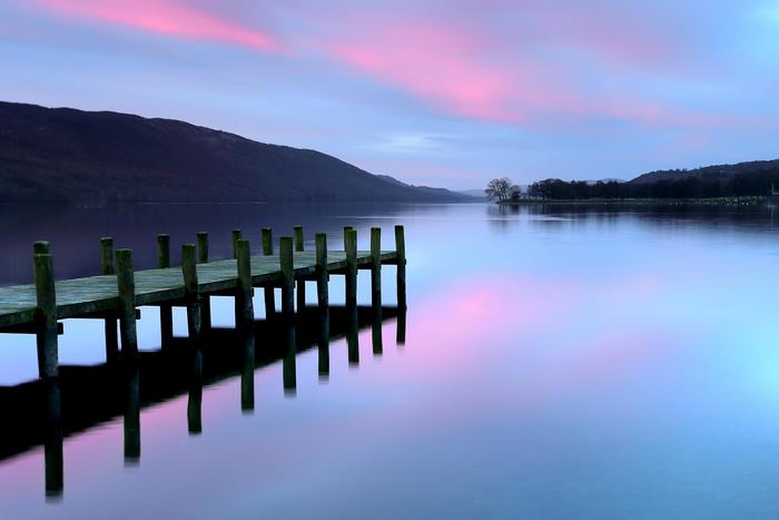 Wooden pier on a lake at dusk with pink and blue clouds