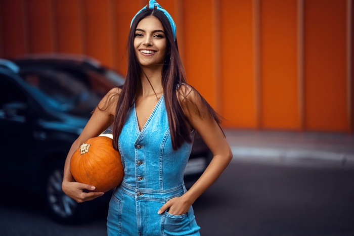 Girl in denim jumpsuit holding a pumpkin