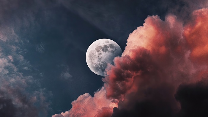 Full moon behind colorful clouds
