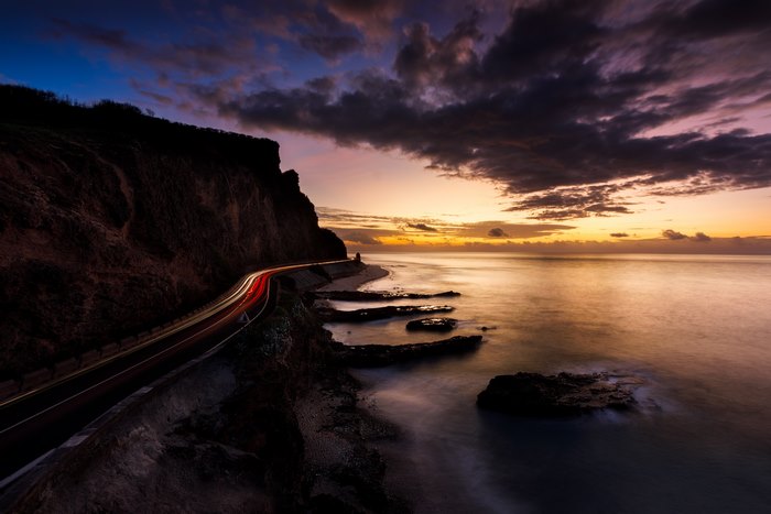 Coastal road with light trails at sunset