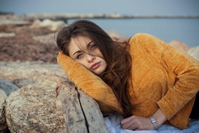 Girl with blue eyes lying on rocks near the sea