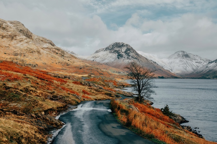 Winding road by a lake with snow-capped mountains