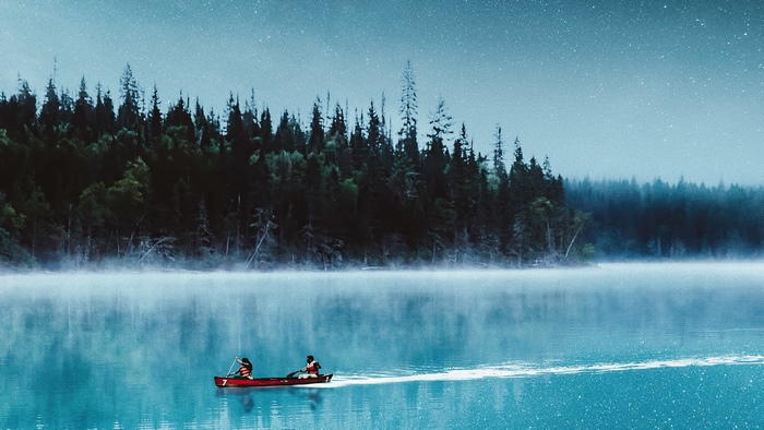 Two people in a canoe on a misty lake at night