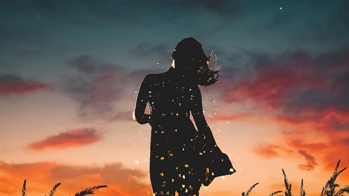 Silhouette of a woman against a sunset sky