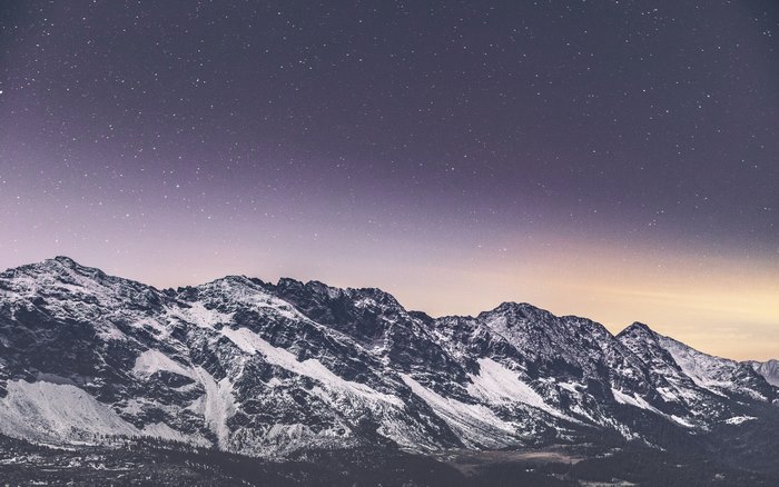 Snow-covered mountains under a starry night sky