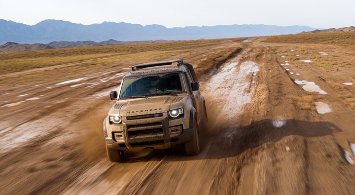 Land Rover Defender driving on a muddy dirt road