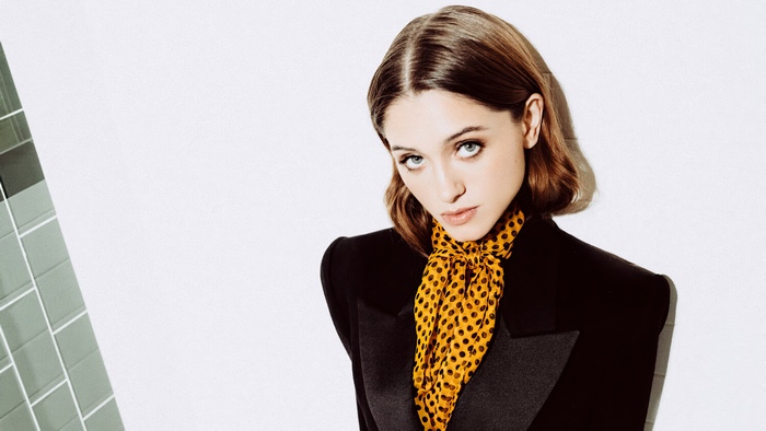 Natalia Dyer in a black blazer with a yellow polka dot scarf