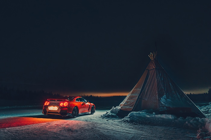 Red Nissan GT-R parked next to a teepee in snow