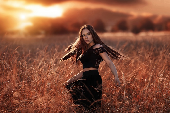Woman in black outfit in a field at sunset