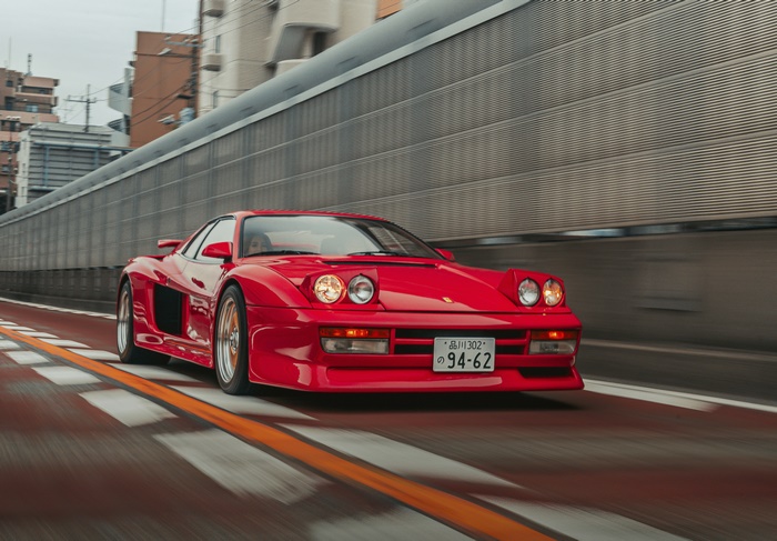 Red Ferrari Testarossa driving on a city road