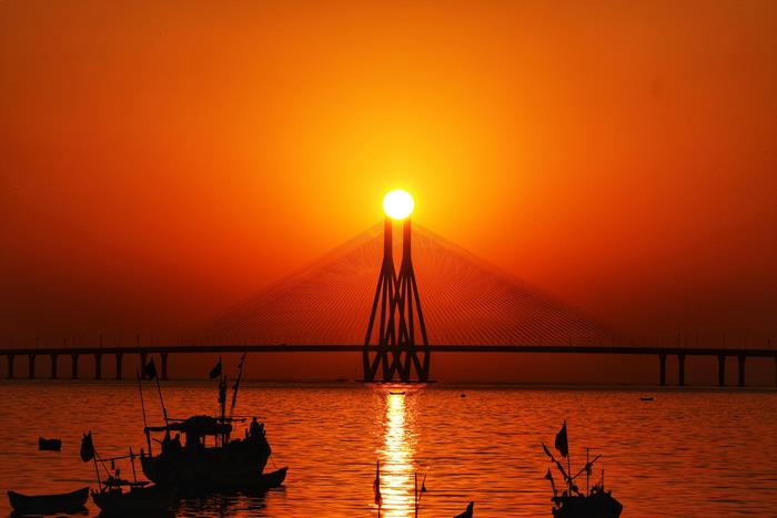 Sunset over the sea with a bridge and boats