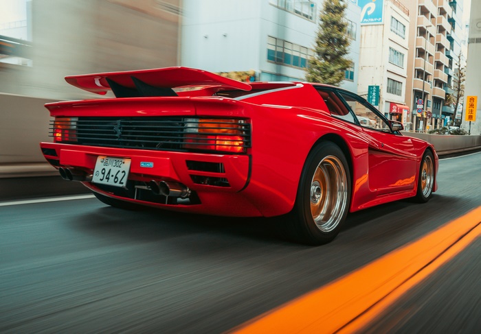 Red Ferrari Testarossa driving on a city street