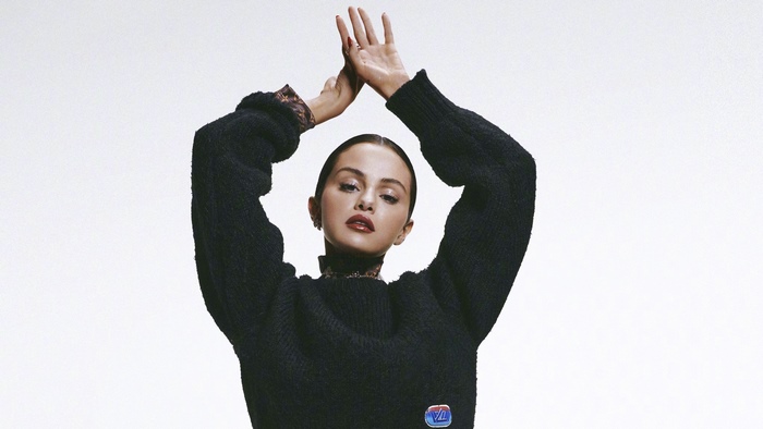 Selena Gomez posing in a black sweater