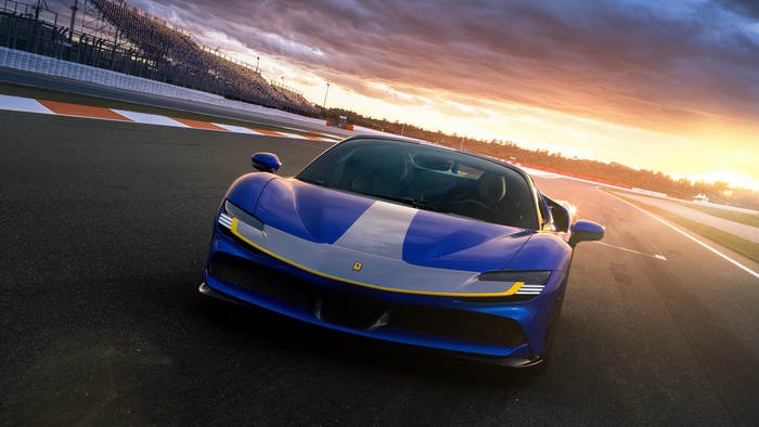 Blue Ferrari SF90 Spider on a race track at sunset