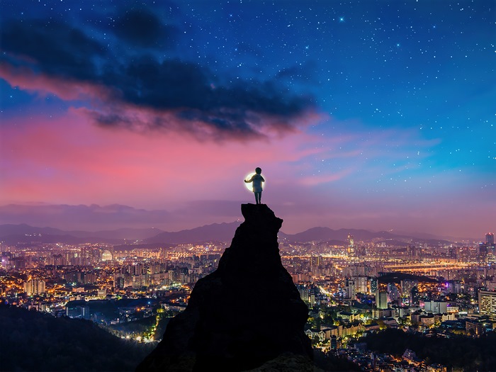 Child on cliff overlooking city at night