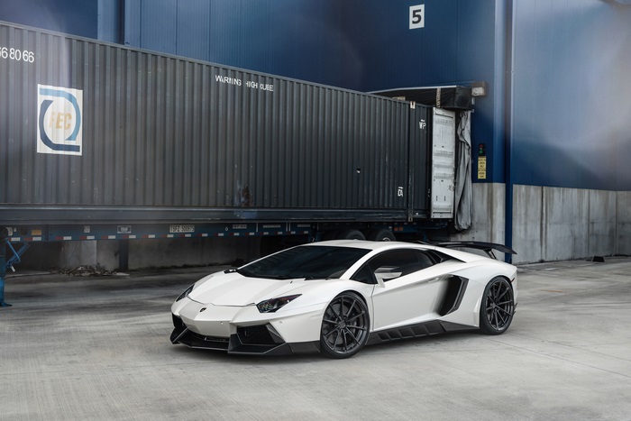 White Lamborghini Aventador parked near shipping containers